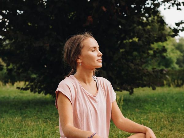 Profile of a person with closed eyes, practicing mindful breathing in nature.