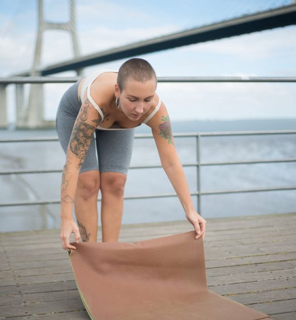 Woman in a serene tree yoga pose on a wooden deck by the sea.